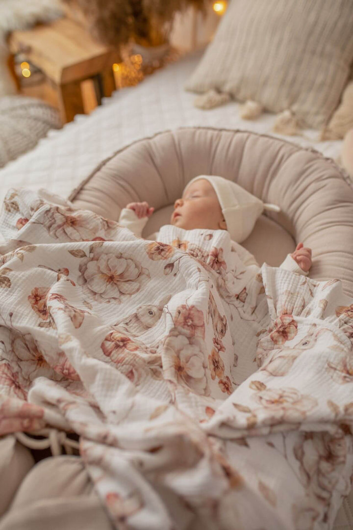 Baby napping in a beige linen baby nest