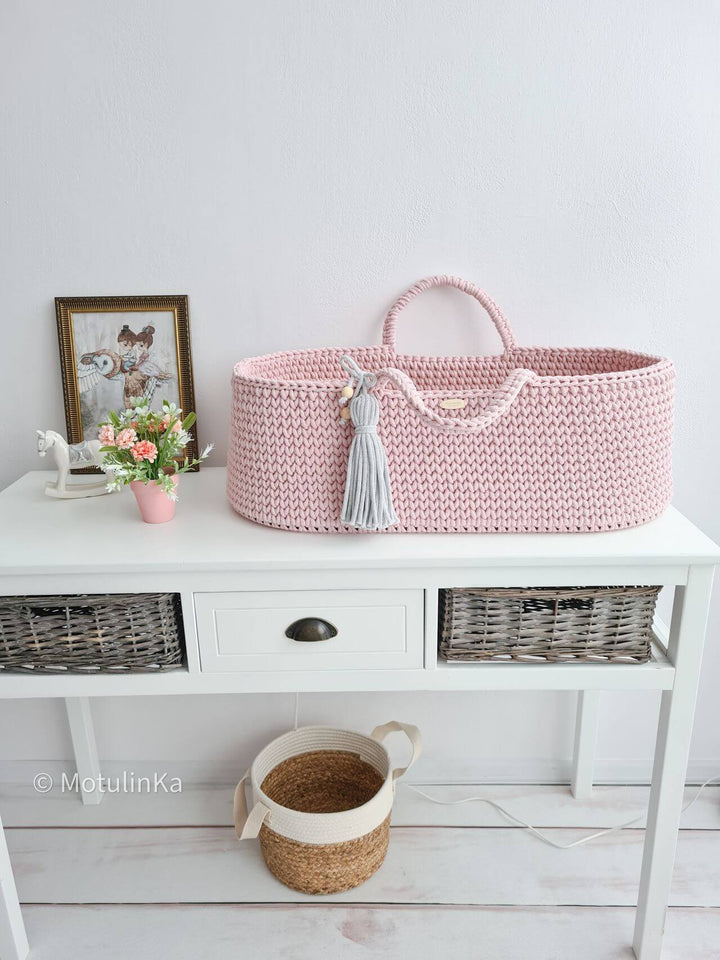 Pink handmade crochet moses basket in a nursery room