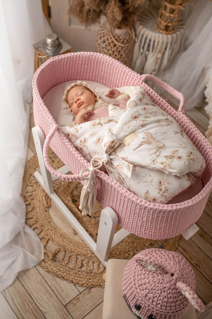 Baby girl sleeping in a pink handmade crochet moses basket